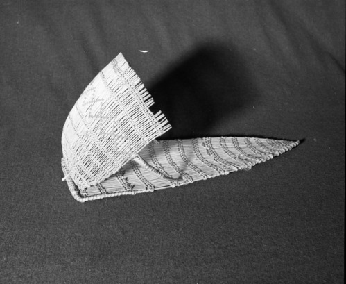 Marie Rozier Collection, Catalog No. 37. Object: Miwok model cradle. Dimensions: 19 x 7". Materials: willow shoots, split shoots, red thread. Technology: diagonally twined, alternate row direction on hood, up to right slant on backboard. Collection History: Alice Reade Collection. Photographed by Michael Dixon in December 1982. Catalogued by Craig Bates and Barbara Beroza. Yosemite Collections, National Park Service.