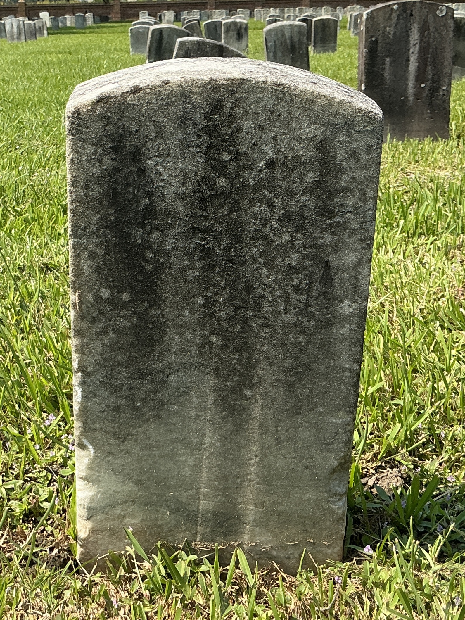 Back of historic upright marble headstone with recessed shield face.