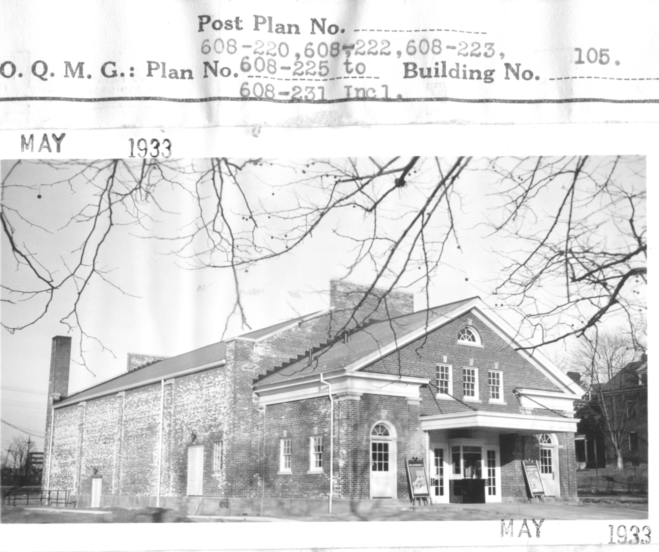 The front of the building has several doors along the front.  The middle door  largest is the with an overhang.  This area appears to have a ticket booth with doors on either side.   There are two additional doors to the side of the central area.  The long side of the building has two doors but no windows.. 