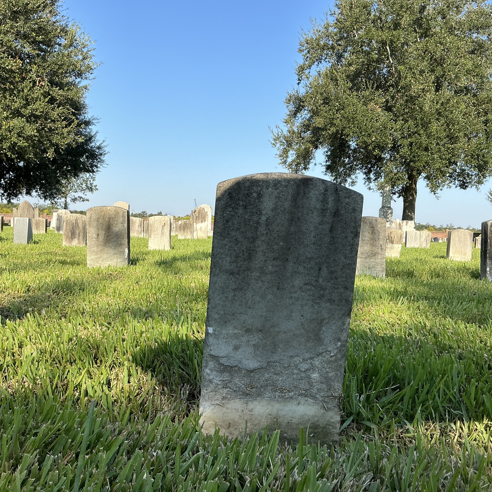 Back of historic upright marble headstone with recessed shield face.