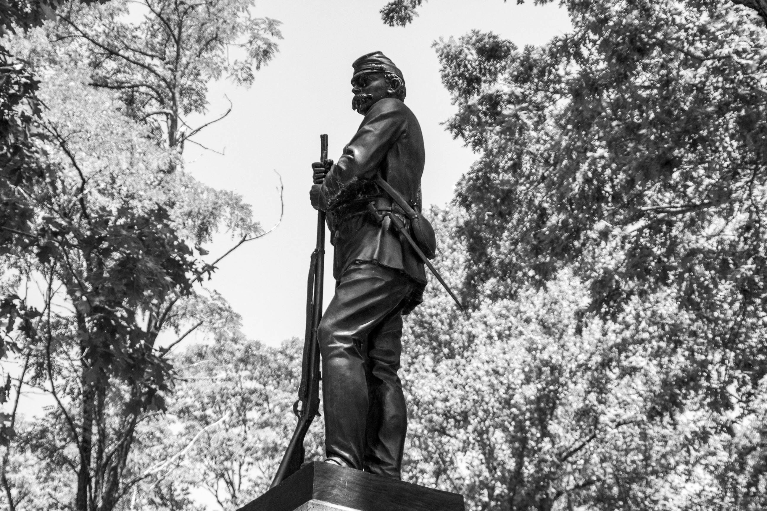 Black and white modern-day photograph of a statue with a Civil War soldier standing while leaning his hands on his musket.