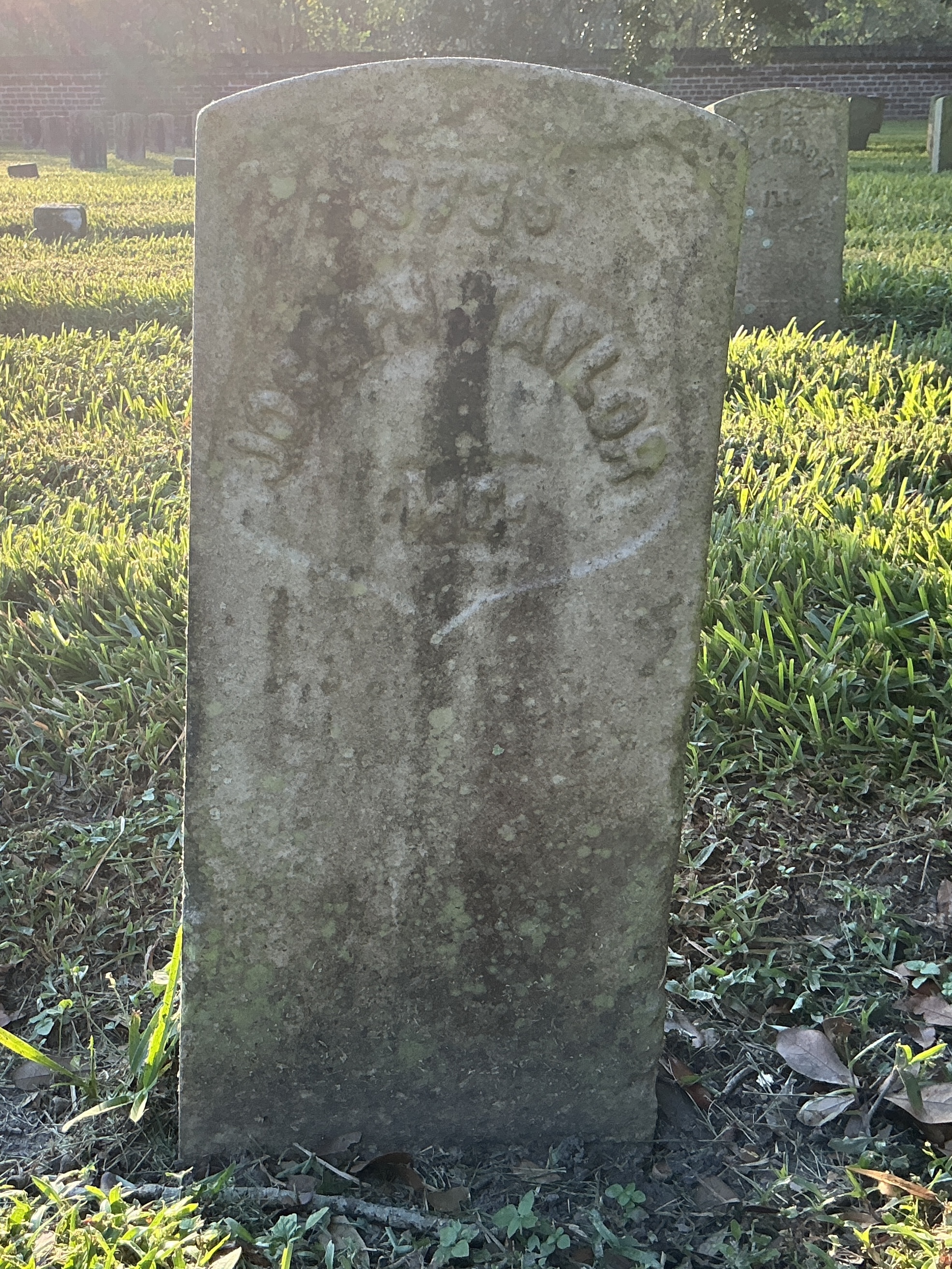 Front of historic upright marble headstone with recessed shield with recessed lettering face.