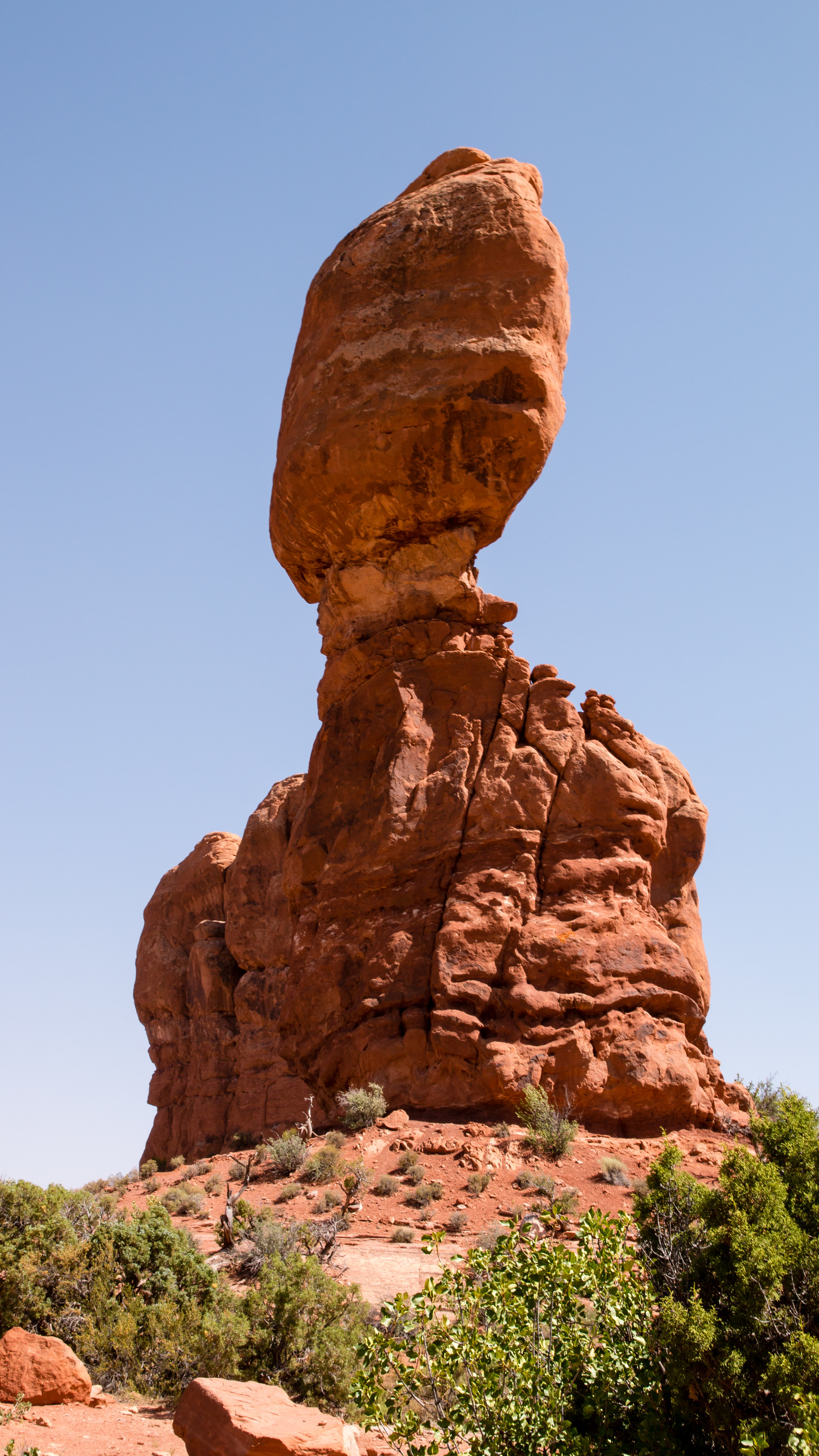 A tall, red stone spire stands in the middle of the desert at Arches National Park. 