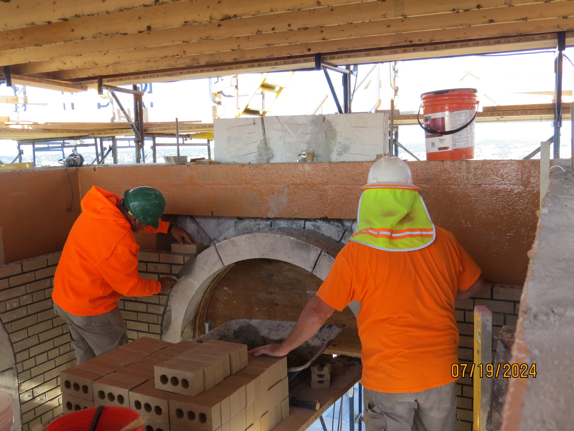 Workers installing brick around an arch inside a structure. 