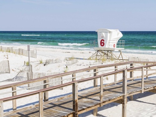 sandy beach with boardwalk and lifeguard stand 
