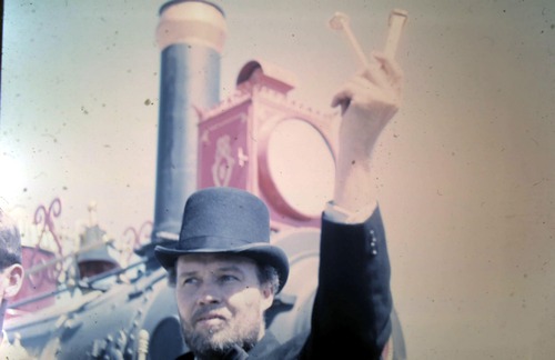 A reenactor holds up two golden spikes. 