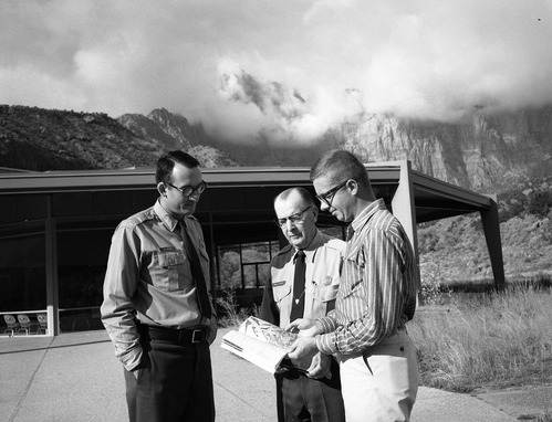 Chief Naturalist Carl E. Jepson (center) stands in front of Mission 66 Visitor Center and Museum with Ranger Roland H. Wauer (left) and Dennis Carter, authors of the 'Birds of Zion' guide book.