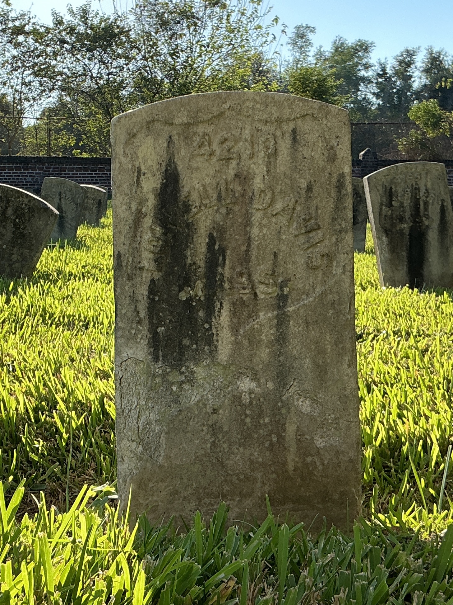 Front of historic upright marble headstone with recessed shield face.