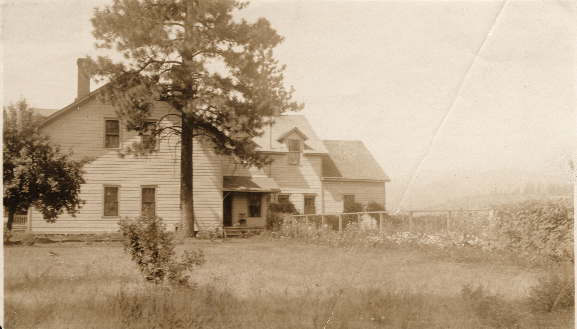Sepia toned photograph of a multistory house with a fenced yard