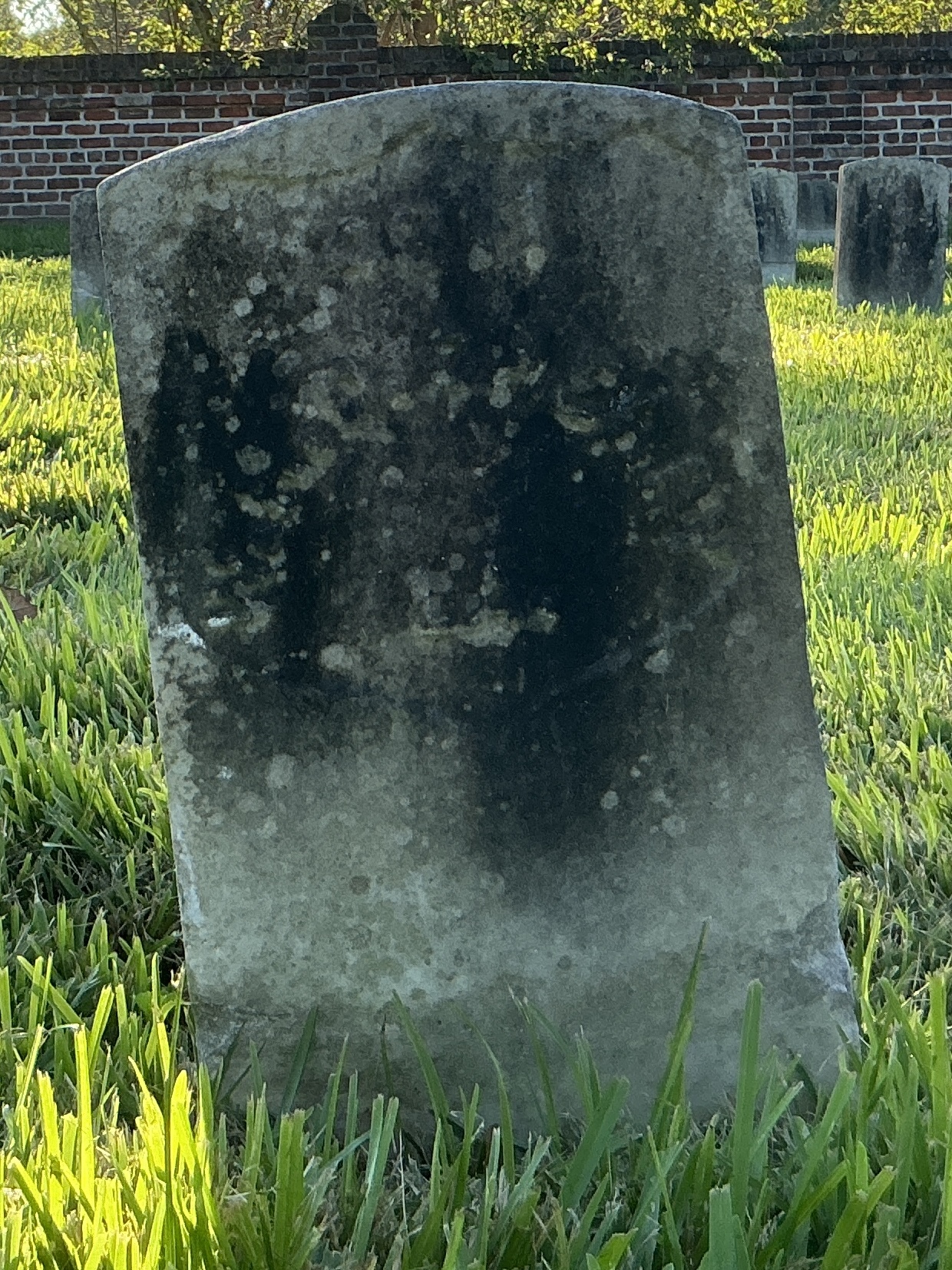 Front of historic upright marble headstone with recessed shield face.