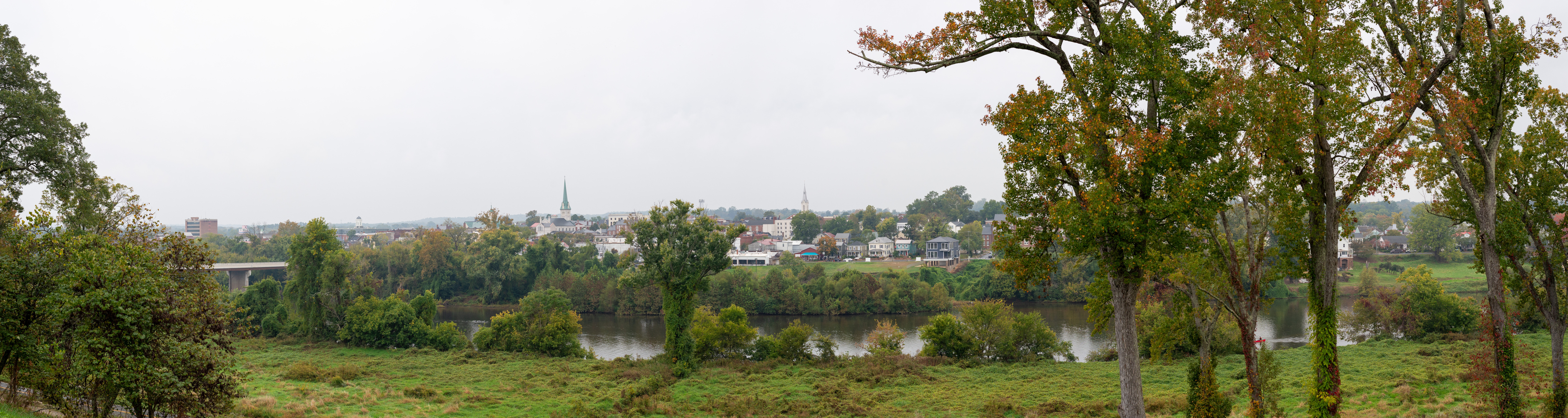 View  across a river to a small town in the distance on a cloudy day.