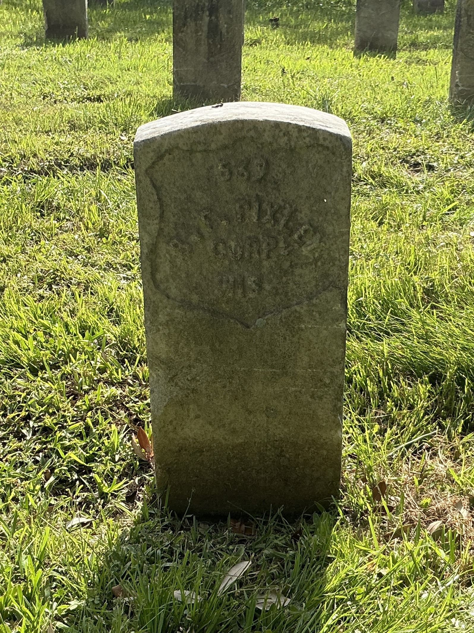 Front of historic upright marble headstone with recessed shield with recessed lettering face.