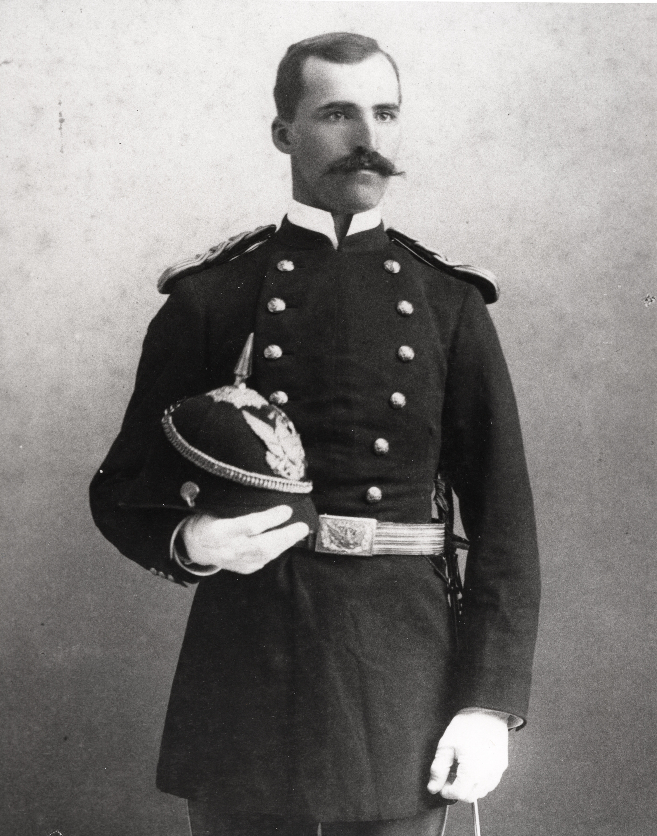 Black and white photograph of a man in a military uniform standing for a photograph