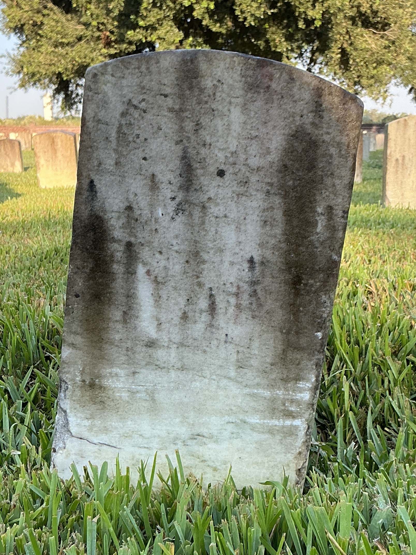 Back of historic upright marble headstone with recessed shield with recessed lettering face.