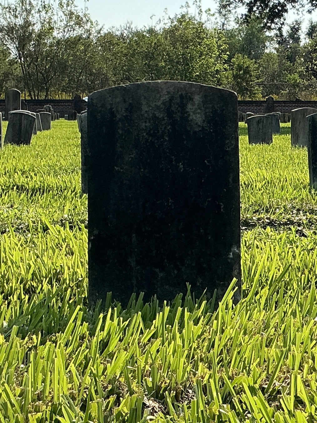 Back of historic upright marble headstone with recessed shield face.