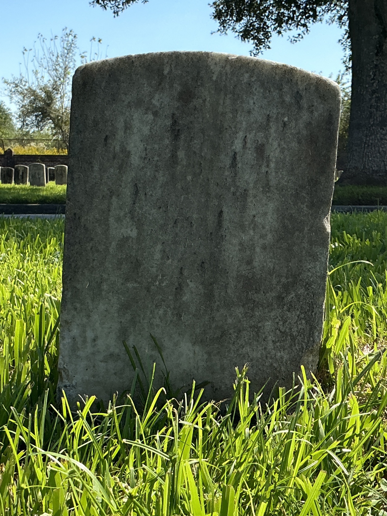 Back of historic upright marble headstone with recessed shield face.