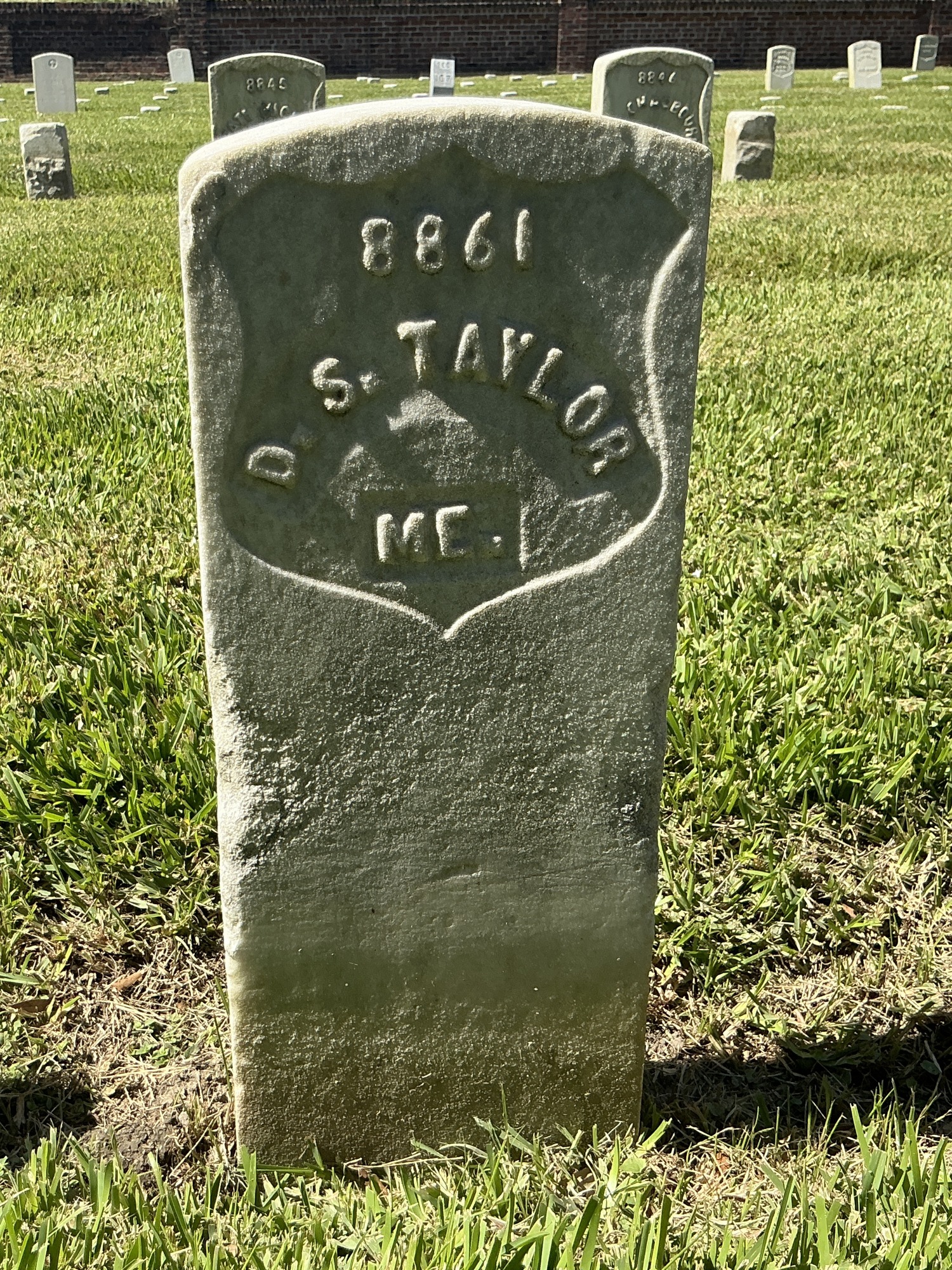 Front of historic upright marble headstone with recessed shield with recessed lettering face.