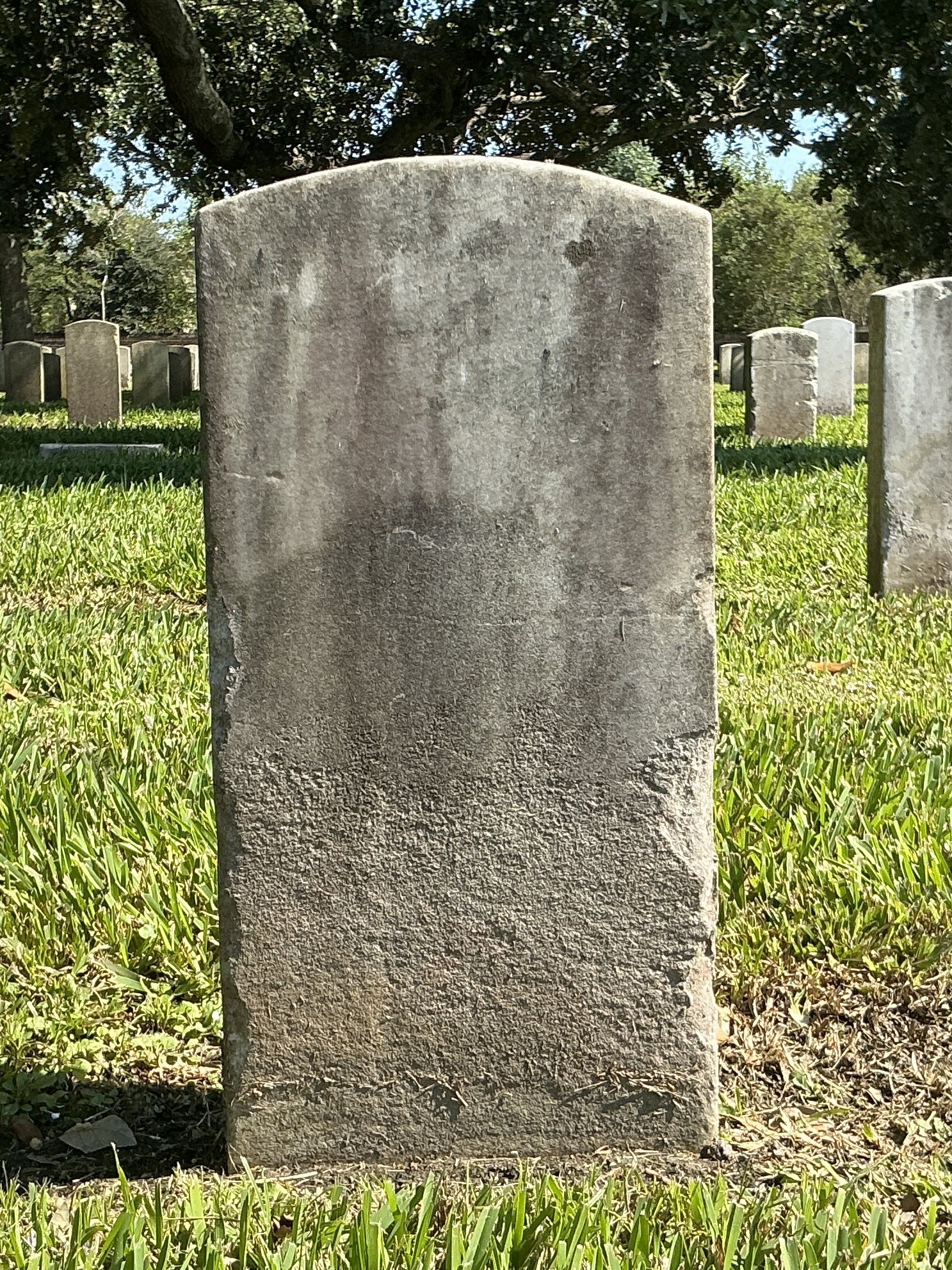 Back of historic upright marble headstone with recessed shield face.