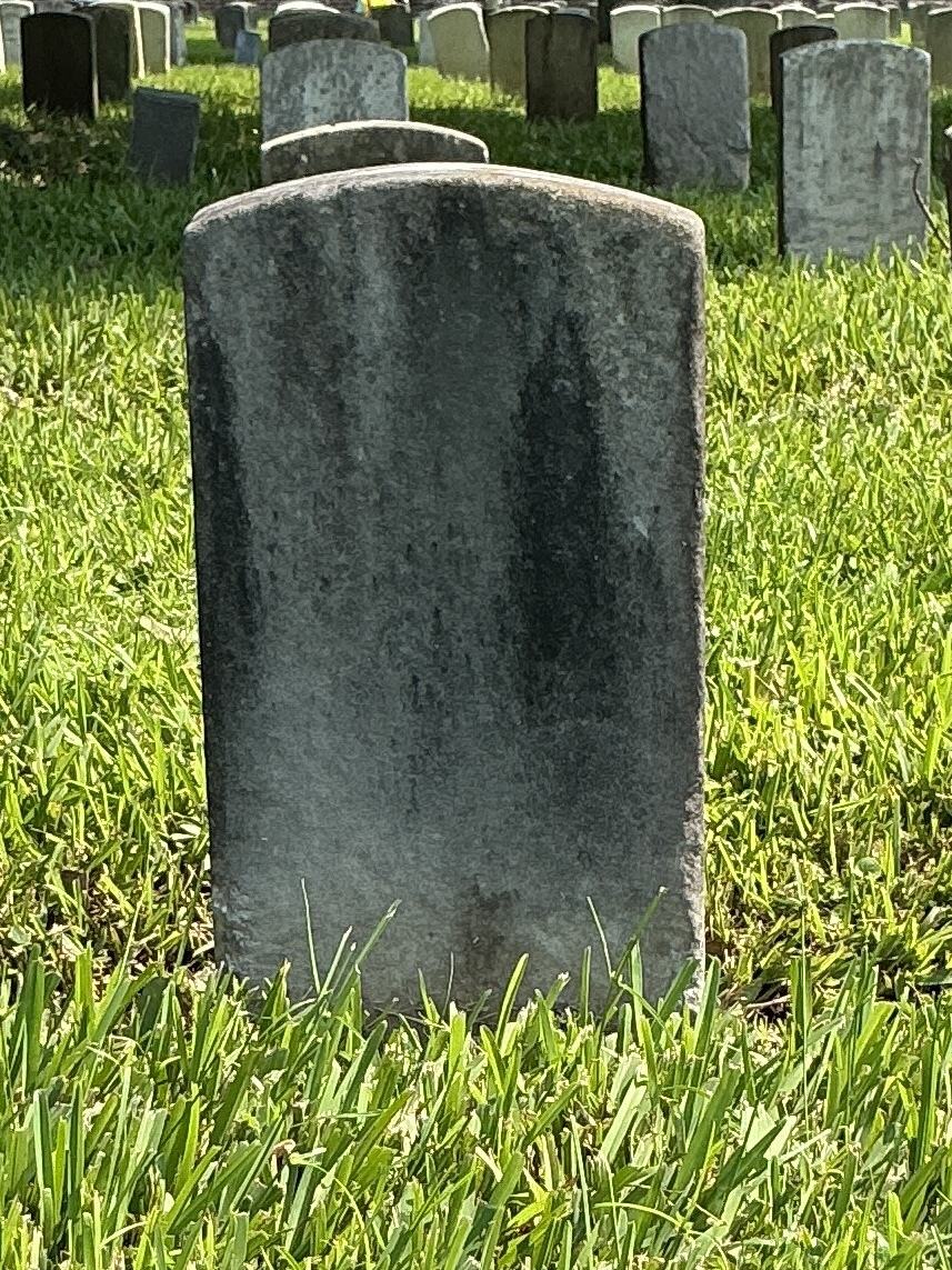 Back of historic upright marble headstone with recessed shield face.
