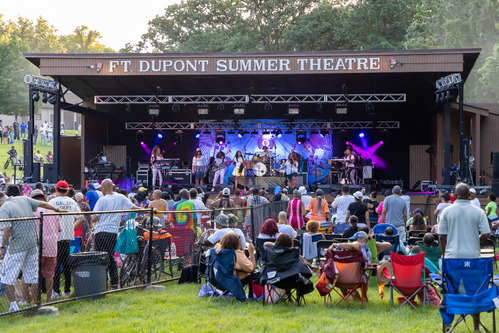 A group of women perform on an outdoor stage. 