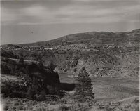 Black and white photograph of buildings on rocky cliffs above a deep canyon.