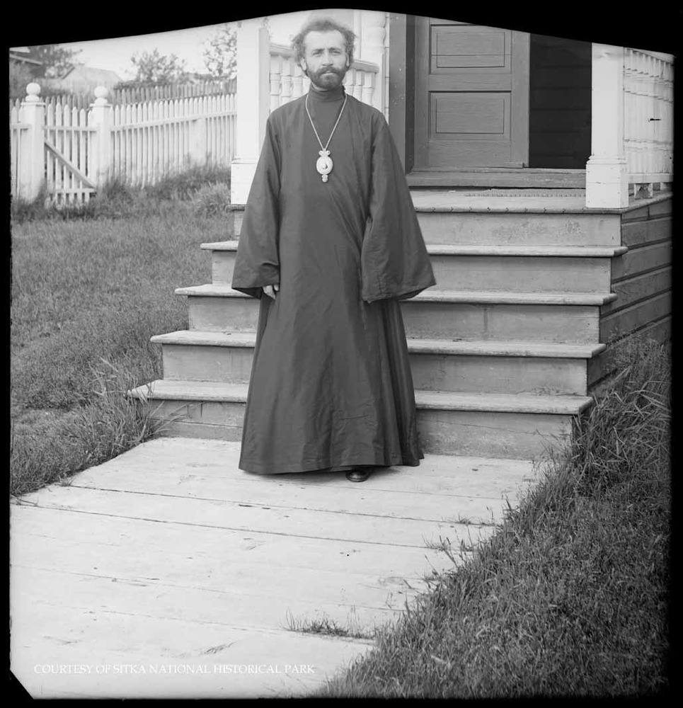 Clergyman in black robes and icon pendant in front of the Russian Bishop's House.