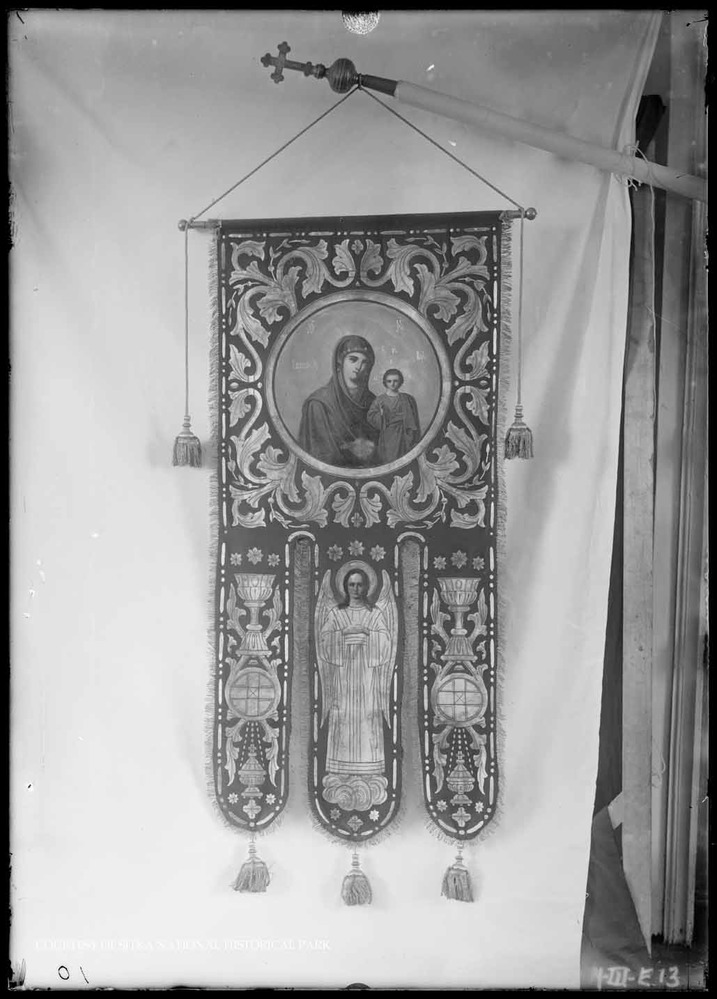 Ecclesiastical banner feature Mary and the Christ Child and an angel hanging from an ornate pole.