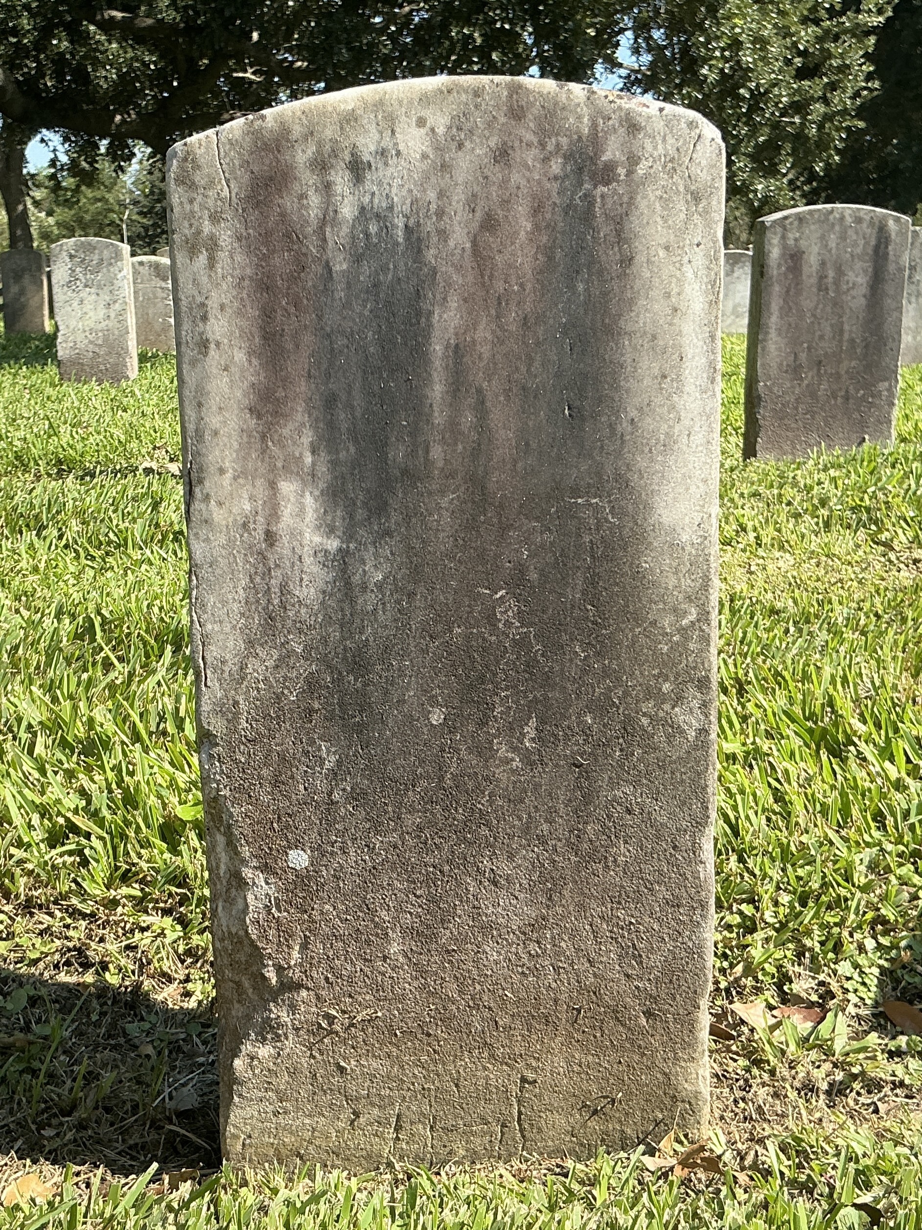 Back of historic upright marble headstone with recessed shield face.
