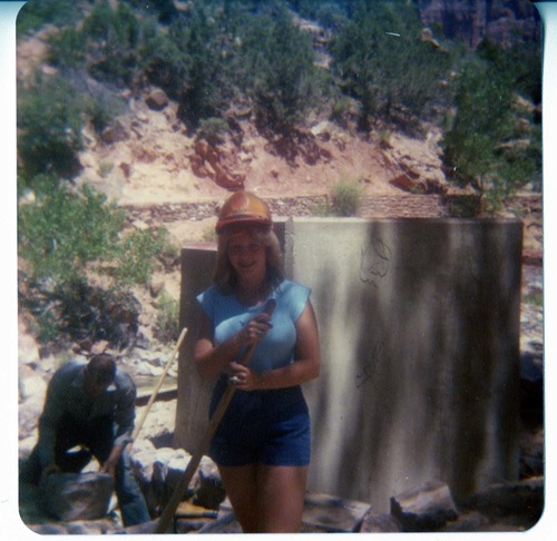 Woman and man working next to concrete and stone abutment for new Grotto footbridge.