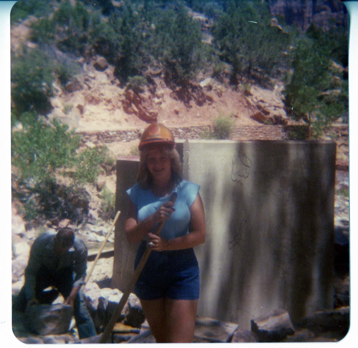 Woman and man working next to concrete and stone abutment for new Grotto footbridge.