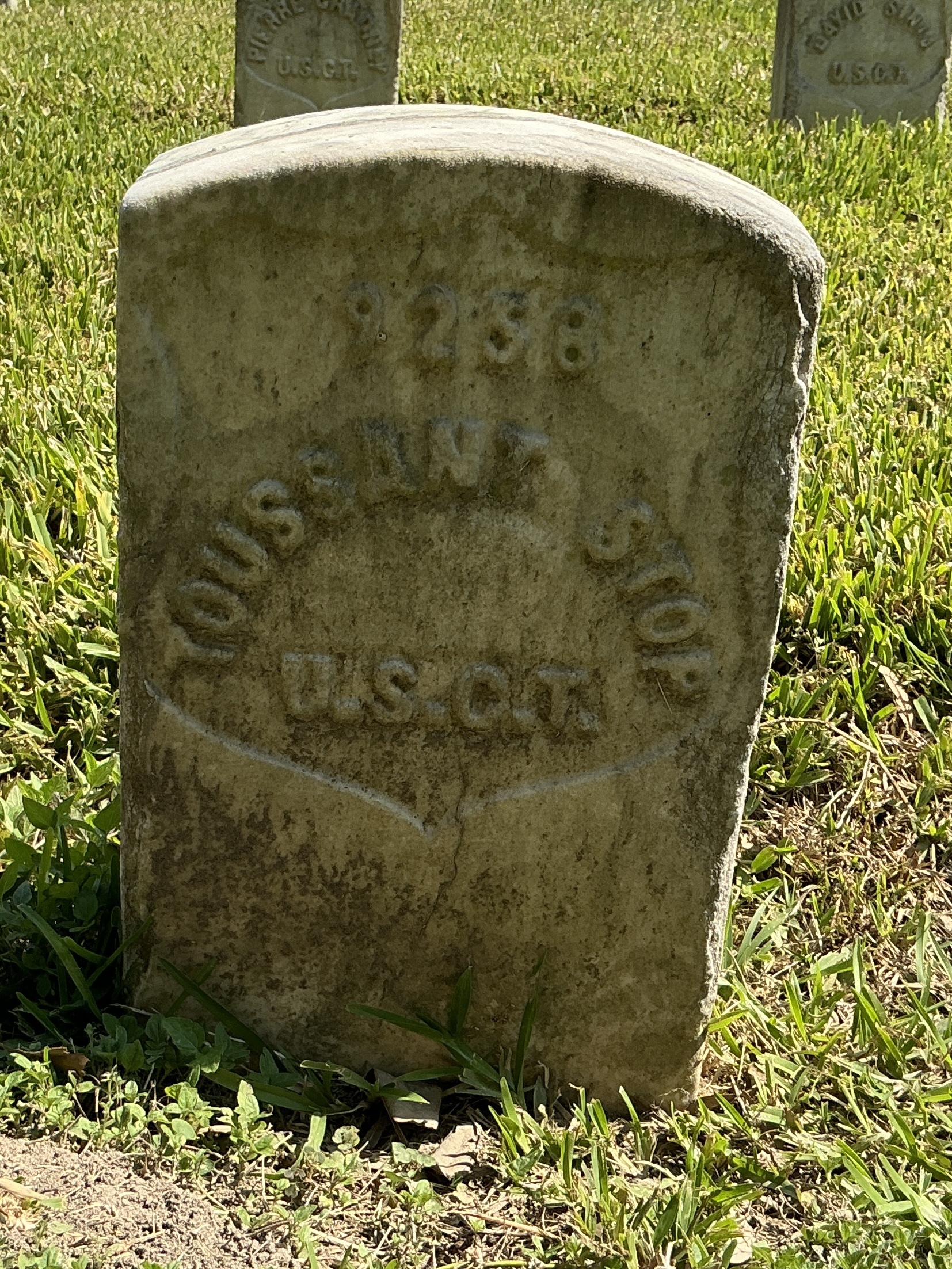 Front of historic upright marble headstone with recessed shield with recessed lettering face.