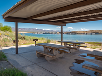 picnic benches under shade structure, marina in distance