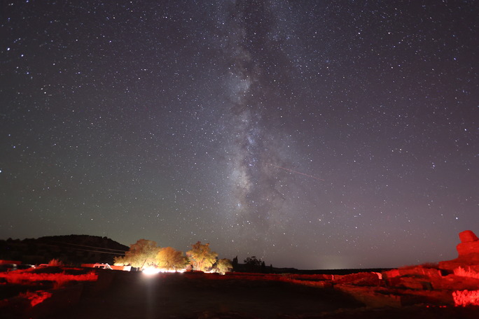 Milky Way in a starry sky with red sandstone church remnants in the foreground.