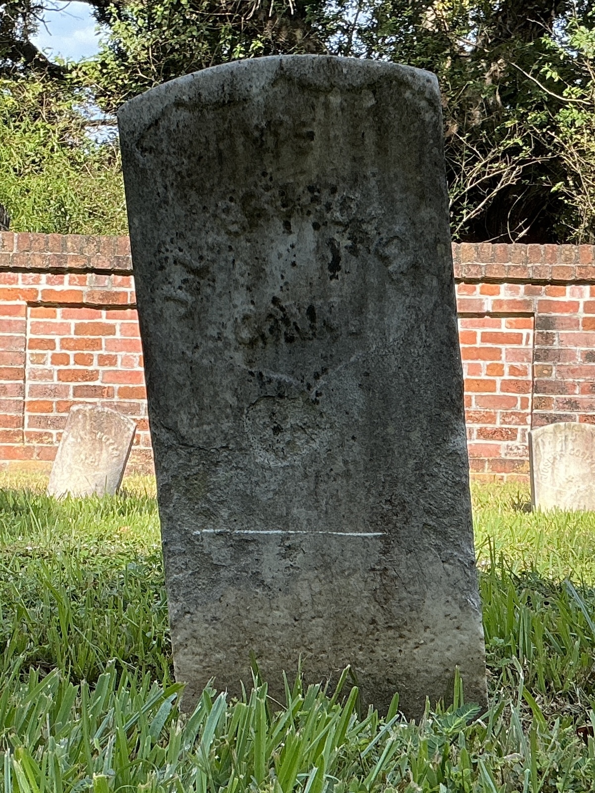 Front of historic upright marble headstone with recessed shield face.