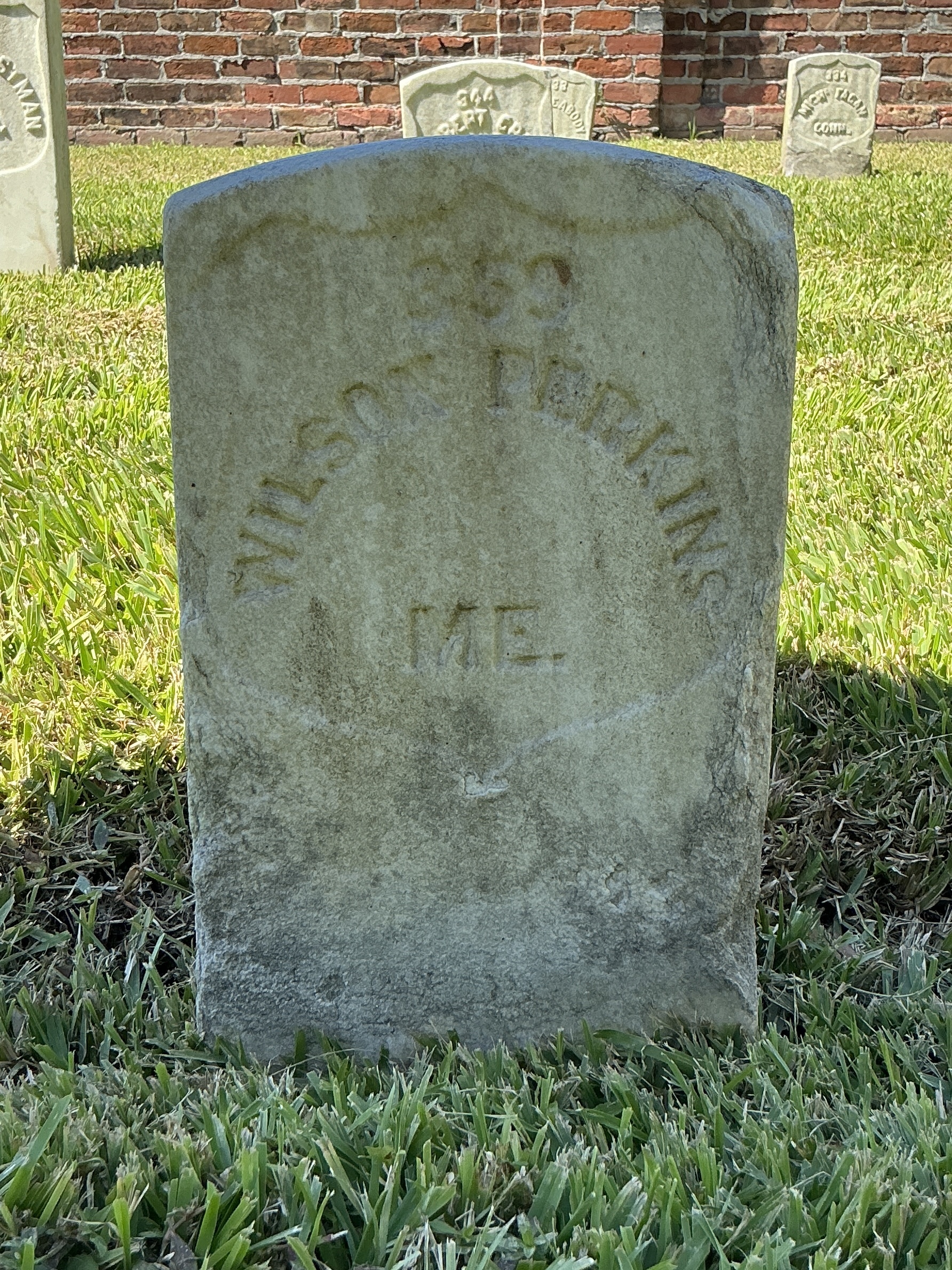 Front of historic upright marble headstone with recessed shield with recessed lettering face.