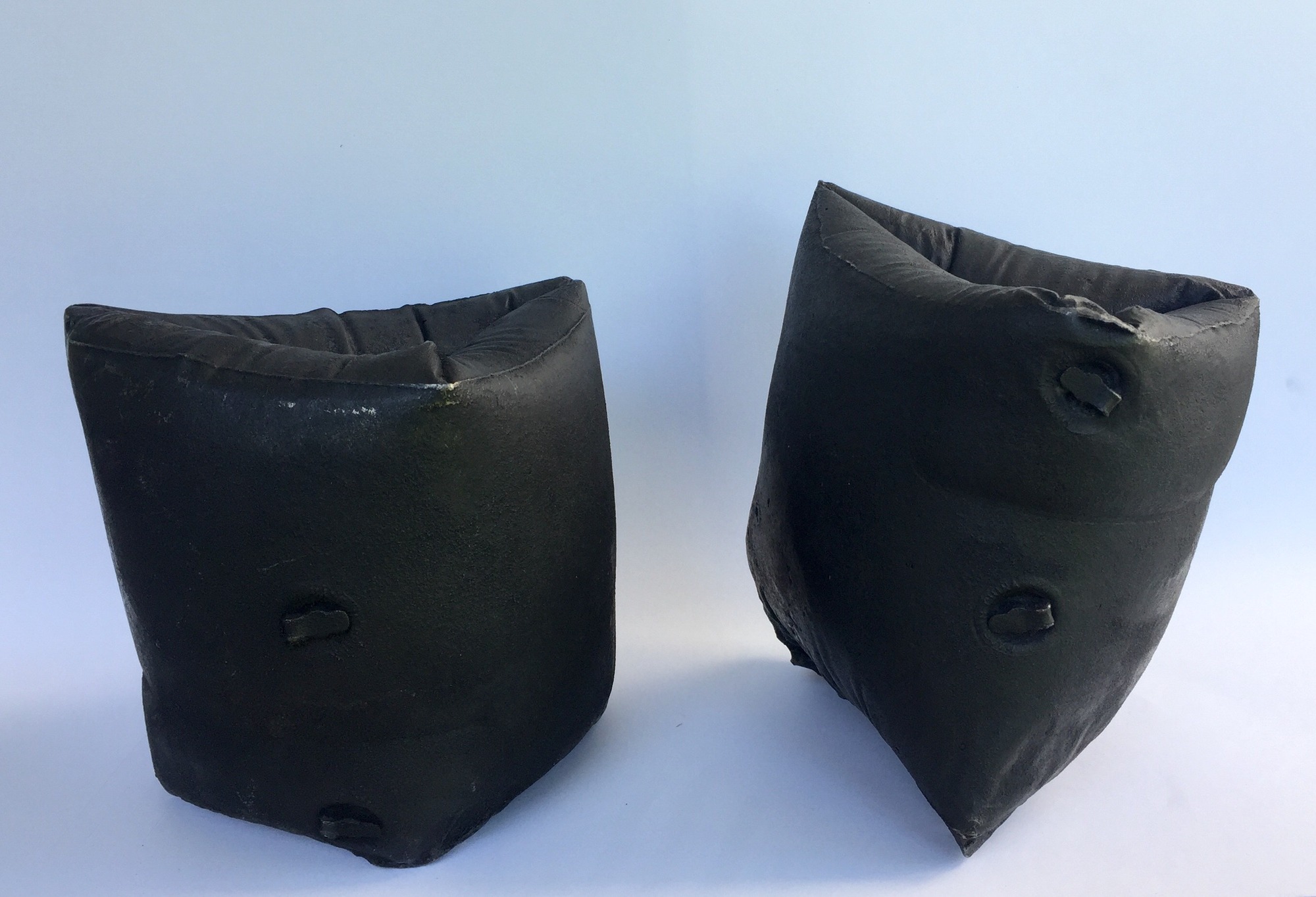 Two black arm swim floaties made from cast iron.