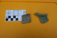 Two pottery rim sherds next to a scale.