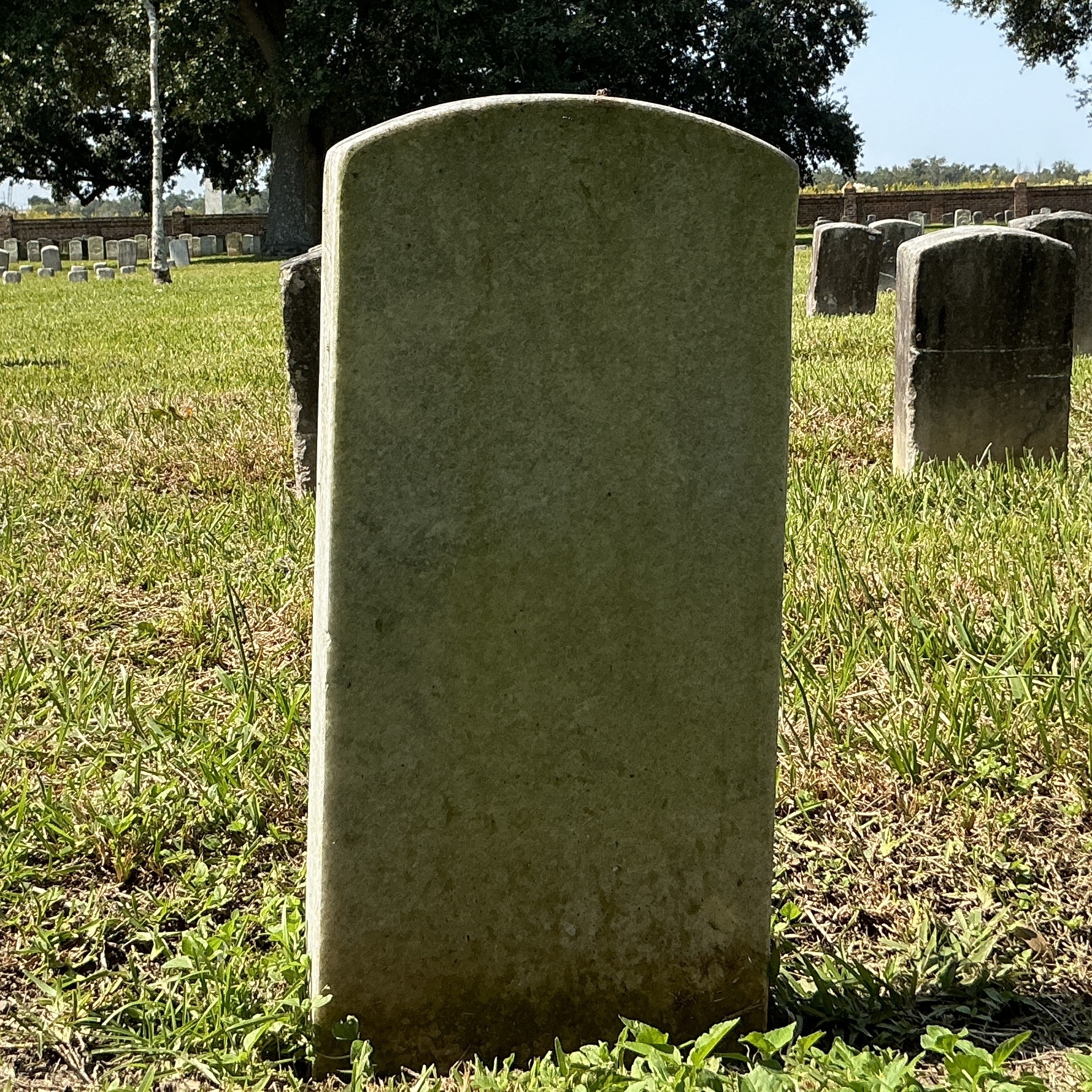 Back of historic upright marble headstone with recessed shield face.