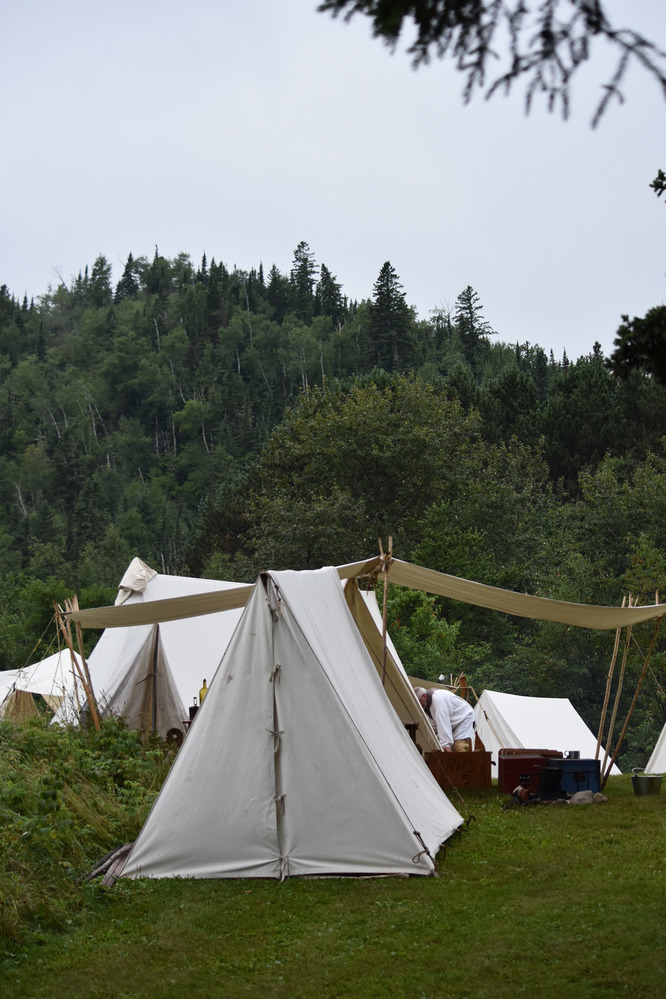 White tents and forested hill.