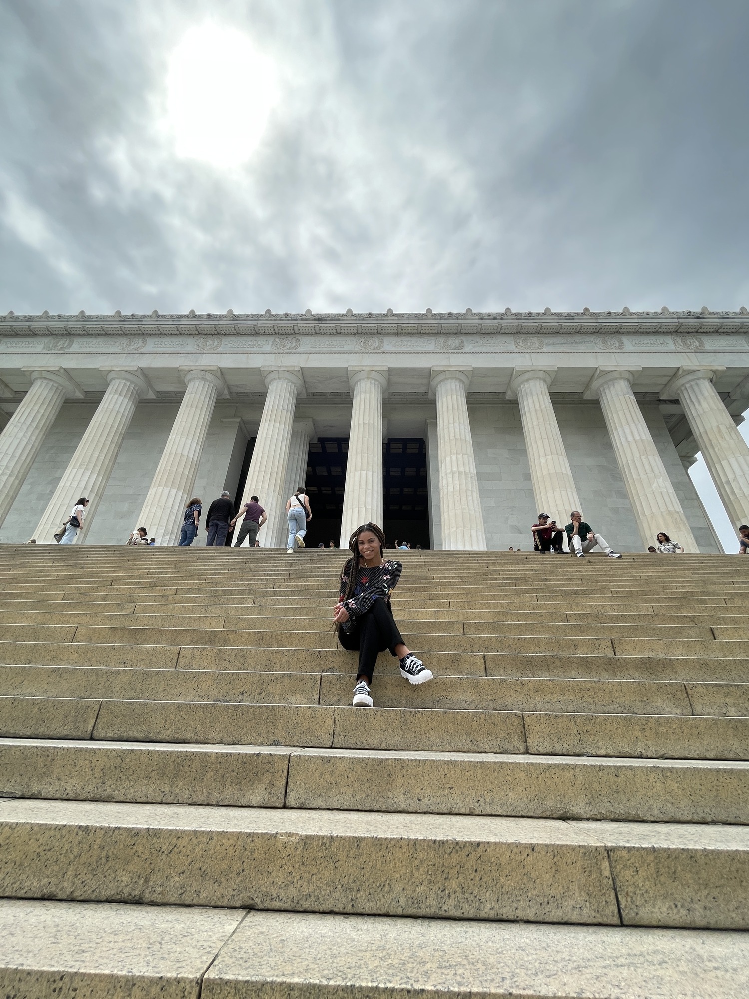Woman sits cross-legged by the stairs leading to the Lincoln Memorial.