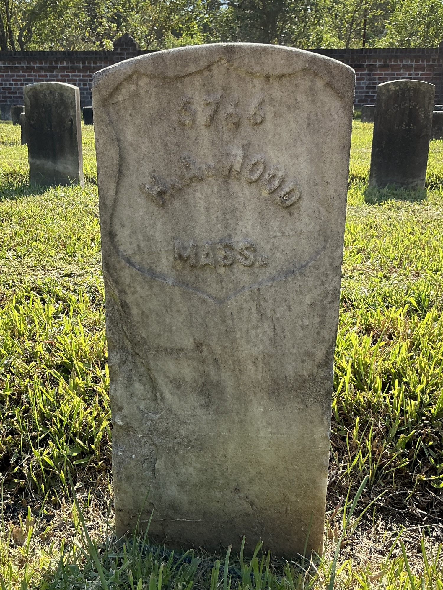 Front of historic upright marble headstone with recessed shield face.