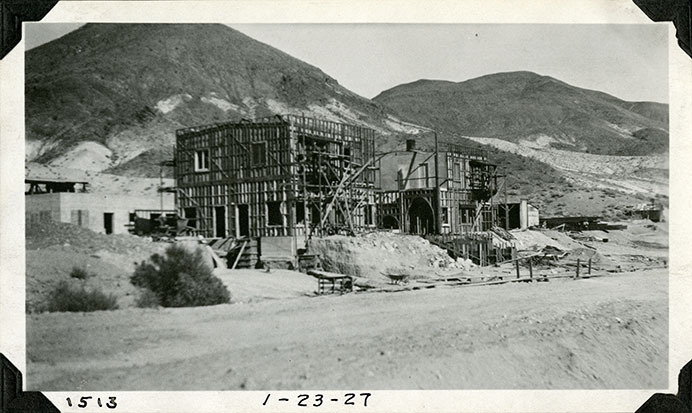 This is an historic black and white photograph from the Scotty's Castle Historic Photograph Collection, Death Valley National Park of Scotty's Castle Main House, looking northeast. Commissary - the future Annex - on left in back ground. January 23, 1927. Photographed by Mat Roy Thompson.