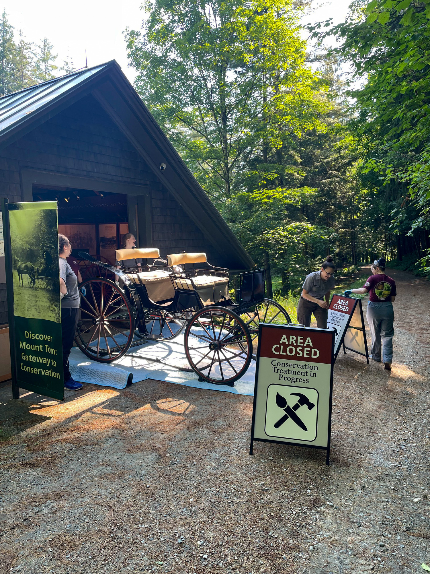 Surrey Carriage on tarps outside of the Woodshed with Cultural Resource staff putting up “Area Closed Conservation Treatment in Progress” 