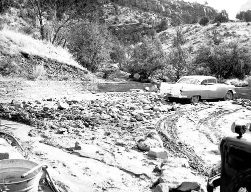 Debris swept into parking area at dormitory by flood. Partially marooned car, ranger dorm.