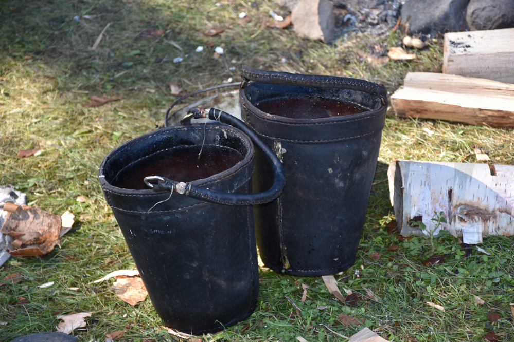 Two black leather buckets near a fire ring.