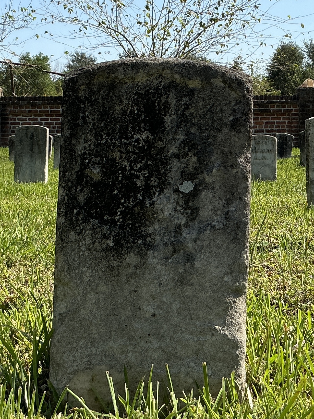 Front of historic upright marble headstone with recessed shield face.