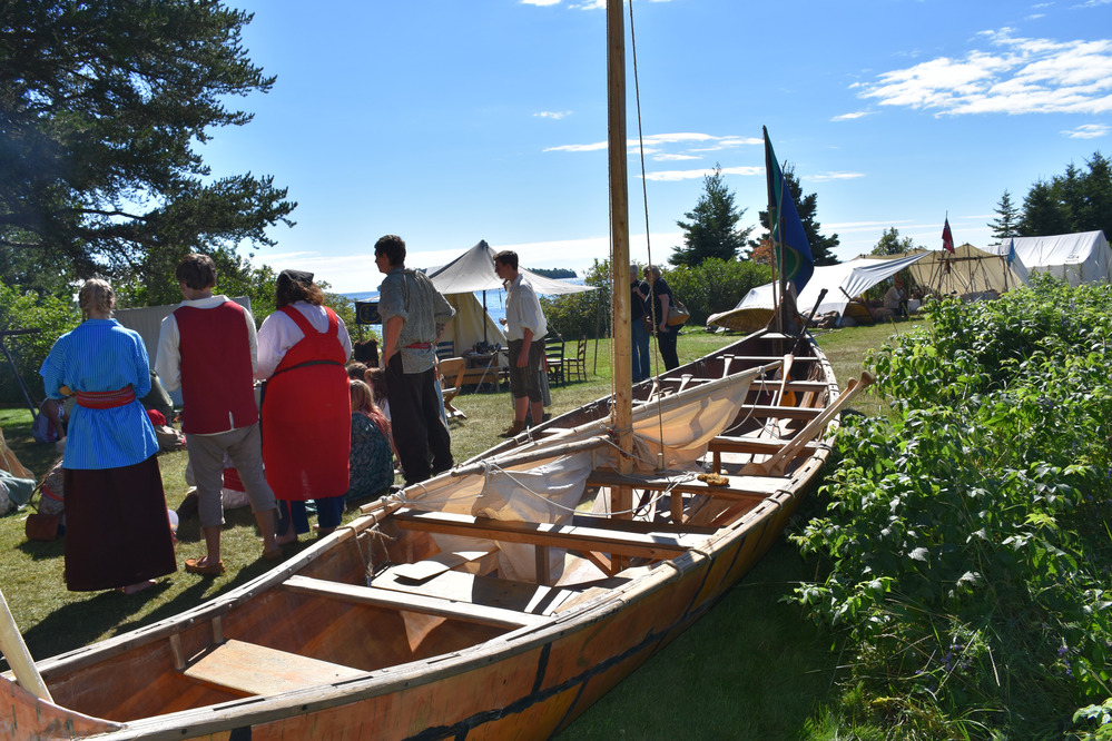 Bark canoe and reenactors watching a fire making contest.