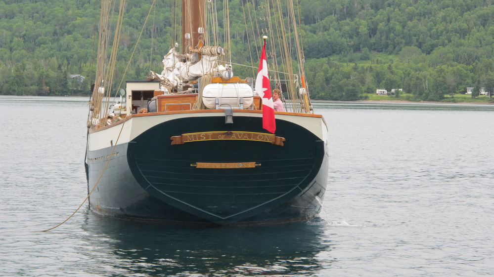 Stern of schooner, houses on shore.