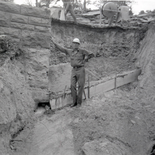Man resting against retaining wall during repairs along East Rim road.