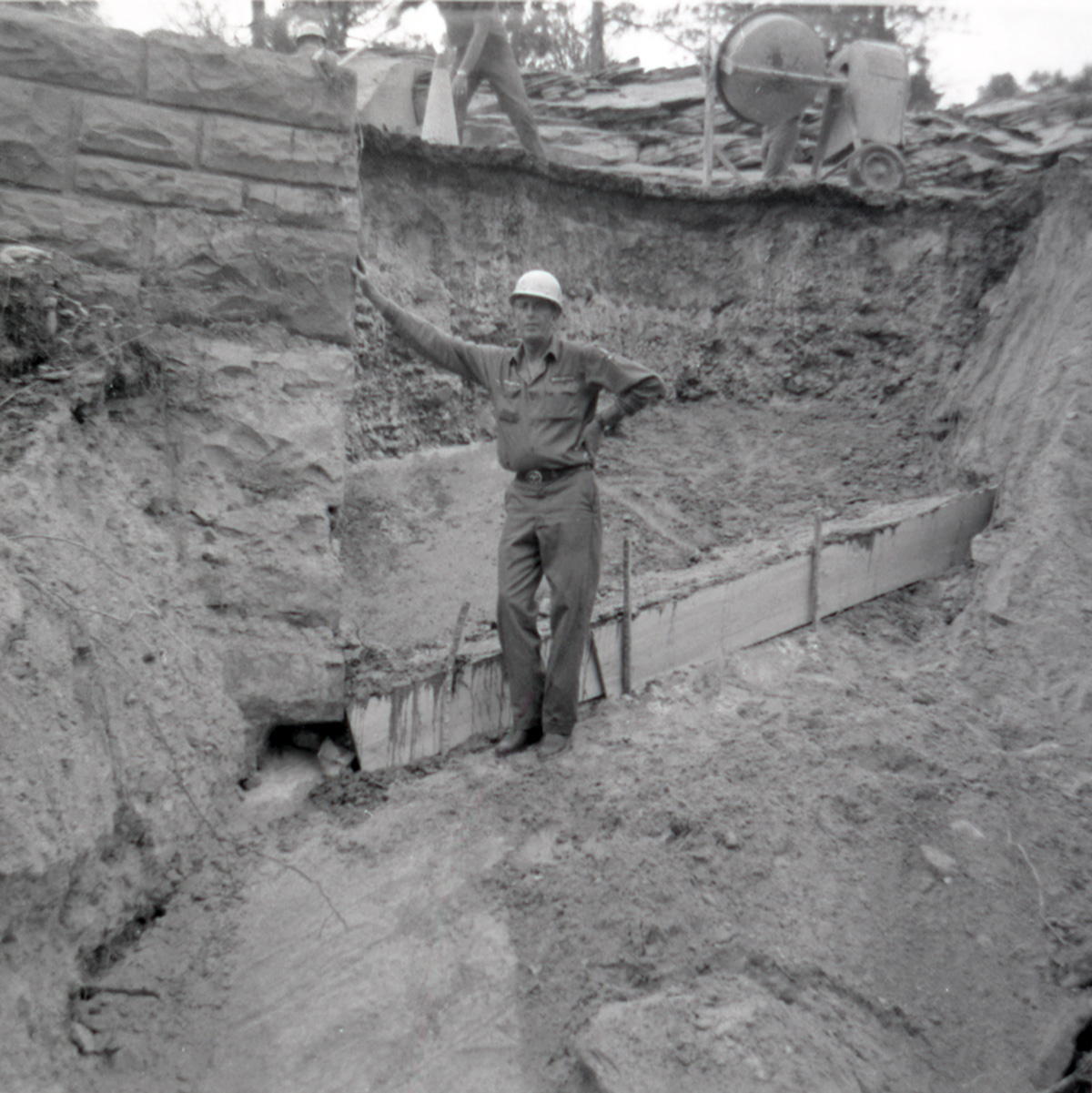 Man resting against retaining wall during repairs along East Rim road.